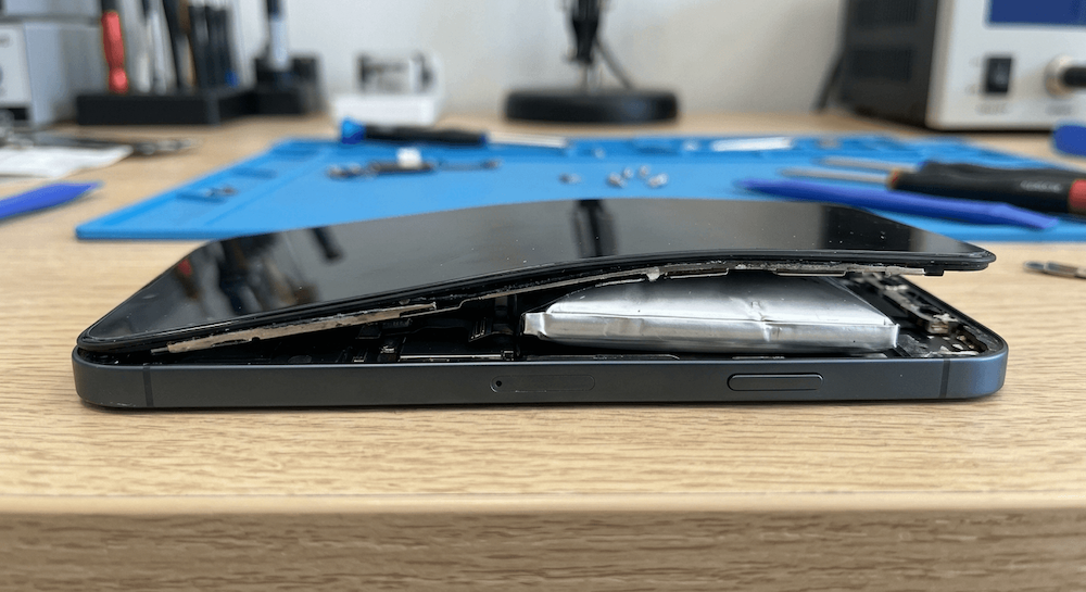 Zdjęcie przedstawia spuchniętą bateria w iPhone wraz z wypchniętym wyświetlaczem